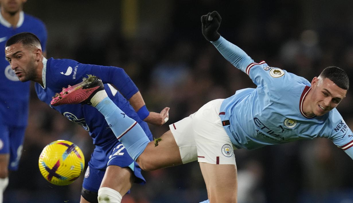 Gelandang Manchester City  Phil Foden berebut bola dengan gelandang Chelsea Hakim Ziyech  pada matchday ke-18 Liga Inggris di Stadion Stamford Bridge, Jumat (6/1/2023) dini hari WIB. Manchester City sukses membungkam Chelsea 1-0 lewat gol kemenangan dicetak Riyad Mahrez pada babak kedua. (AP Photo/Kirsty Wigglesworth)