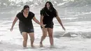 Dua wanita saat masuk ke air di Huntington Beach, California, Senin (11/10/2021). Pantai Huntington membuka kembali garis pantainya setelah hasil pengujian air kembali dengan jumlah racun terkait minyak yang tidak terdeteksi di air laut. (Paul Bersebach/The Orange County Register via AP)