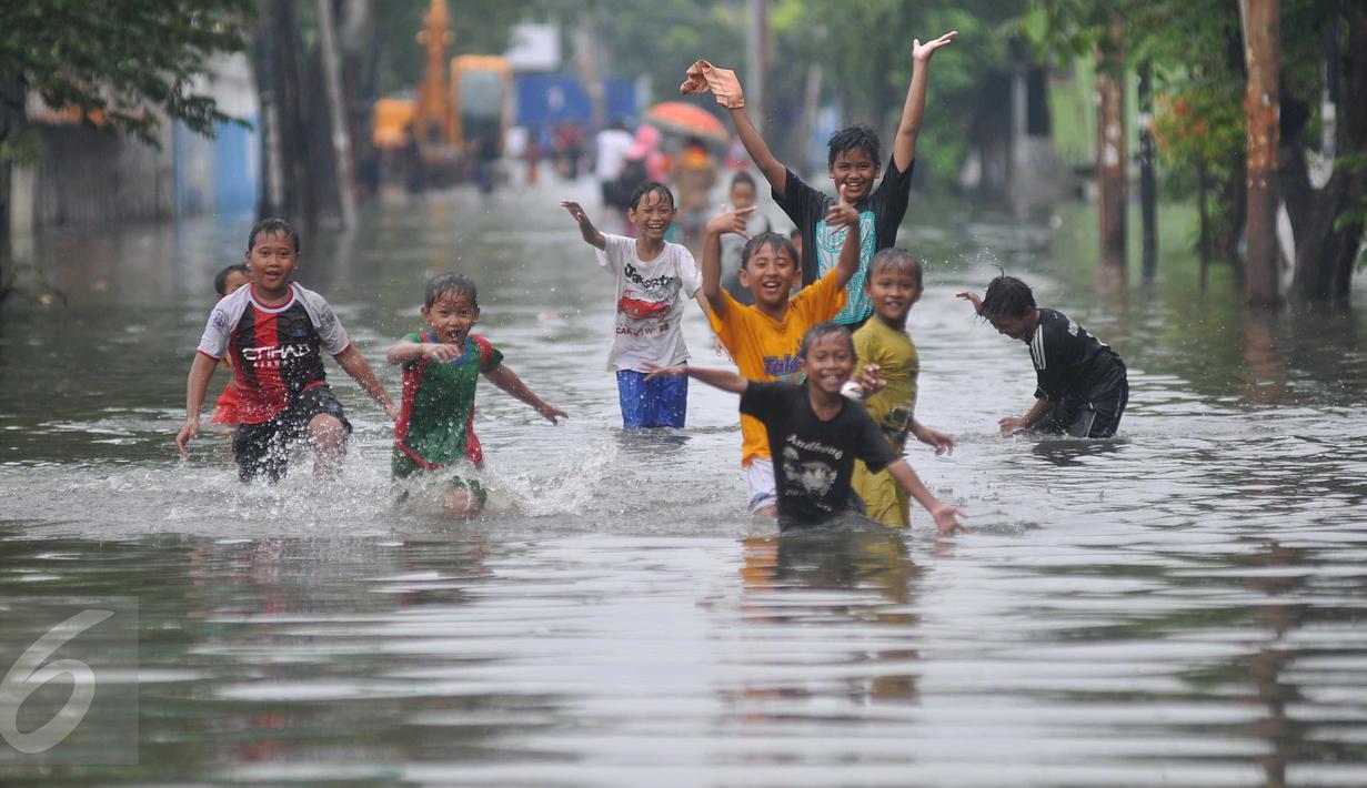 Sejumlah anak bermain saat banjir melanda kawasan Rawa Buaya, Jakarta, Minggu (28/2/2016). Banjir terjadi akibat luapan Kali Mookervart yang diguyur hujan sejak malam. (Liputan6.com/Gempur M Surya)