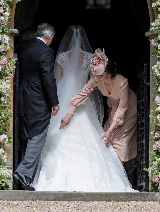 Kate Middleton memperbaiki posisi gaun pengantin sang adik, Pippa Middleton saat memasuki Gereja St. Mark, Sabtu (20/5). Kate tampak anggun ketika mendampingi Pippa menuju pelaminan. (AP Photo/Kirsty Wigglesworth, Pool)
