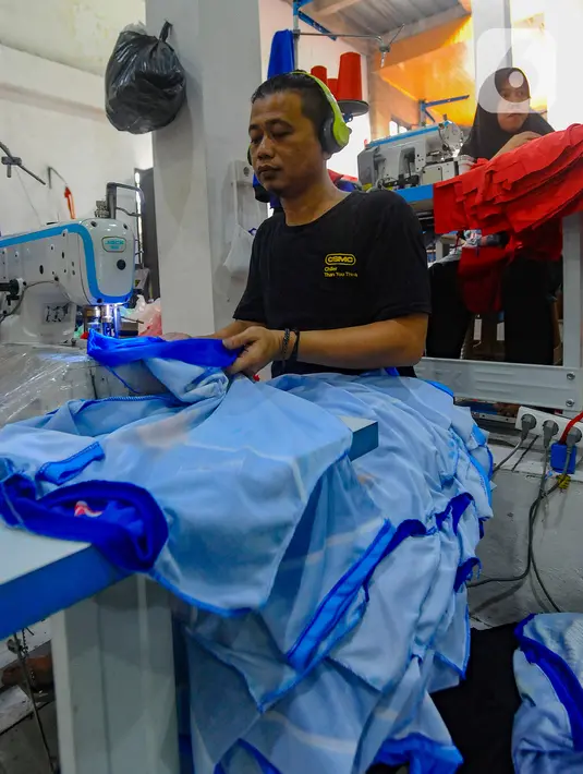 Pekerja menjahit kaus partai politik yang telah disablon di sebuah UMKM konveksi sablon rumahan Sinergi Adv, Srengseng Sawah, Jakarta, Rabu Jumat (25/10/2023). (merdeka.com/Arie Basuki)