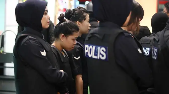 Tersangka kasus pembunuhan Kim Jong-nam, Siti Aisyah dengan kawalan polisi dibawa menuju Bandara Internasional Kuala Lumpur, Selasa (24/10). Siti terlihat mengenakan rompi anti-peluru saat mengunjungi tempat kejadian perkara itu. (AP/Sadiq Asyraf)