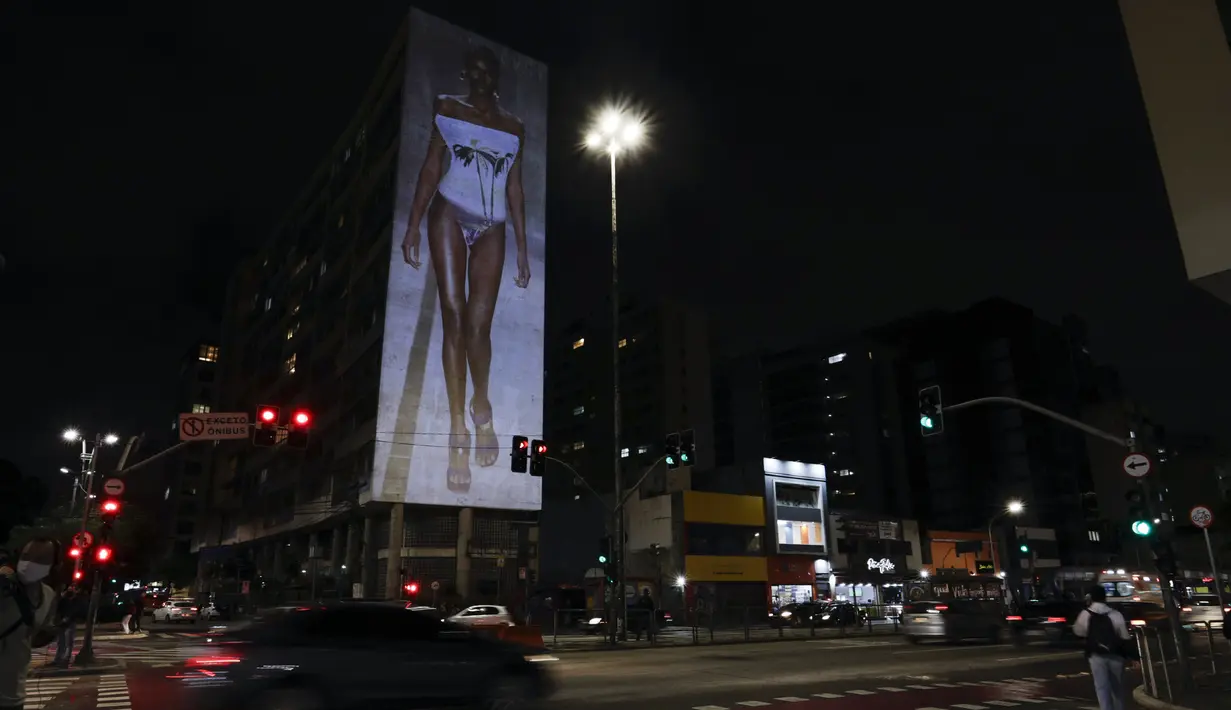 Gambar model di atas catwalk diproyeksikan pada sebuah gedung selama Sao Paulo Fashion Week di Sao Paulo, Brasil, Rabu (4/11/2020). Perancang busana meninggalkan catwalk dan mengandalkan teknologi digital untuk memamerkan karya koleksi spring/summer mereka. (AP Photo/Marcelo Chello)