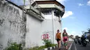Dua turis asing berjalang di sepanjang dinding parimeter Lembaga Pemasyarakatan (Lapas) Kerobokan, Bali, Senin (19/6). Empat narapidana asing kabur melalui lubang sepanjang 15 meter yang mengarah ke parit di luar bangunan Lapas. (SONNY TUMBELAKA/AFP)