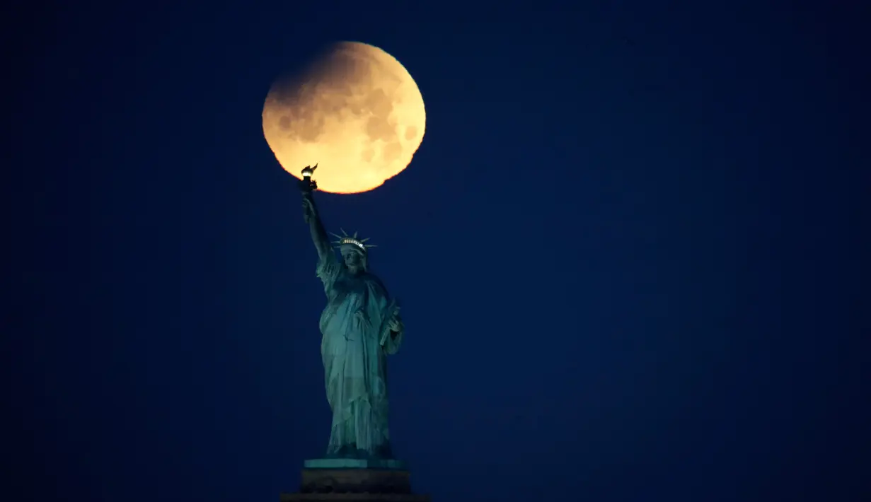 Pemandangan ketika Patung Liberty dihiasi oleh supermoon di Brooklyn, New York, Amerika Serikat, Rabu (31/1). Supermoon adalah di mana bulan berada pada jarak terdekatnya dengan bumi. (AP Photo/Julio Cortez)