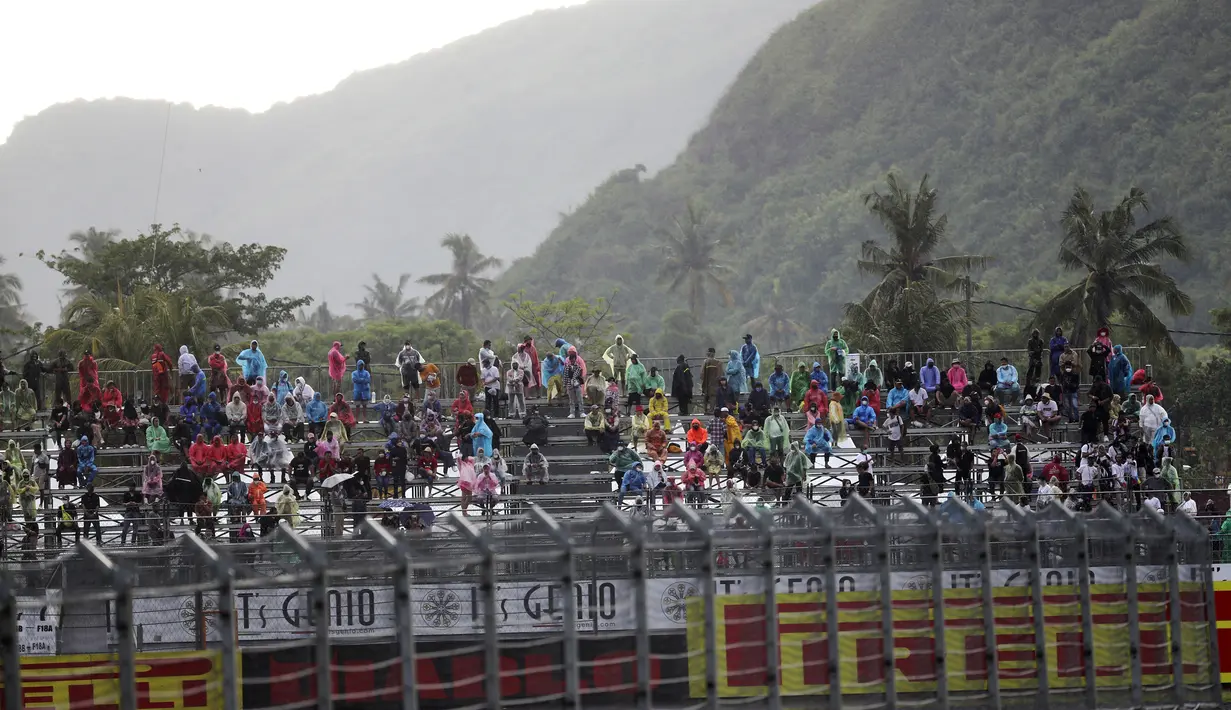 Penonton kehujanan saat hujan lebat sebelum Race 2 WSBK Mandalika 2021 di Pertamina Mandalika International Street Circuit, Lombok, Nusa Tenggara Barat, Minggu (21/11/2021). Balapan dilanjutkan pukul 15.30 WIB atau 16.30 Wita dan hanya digelar 12 lap. (AP Photo/Achmad Ibrahim)