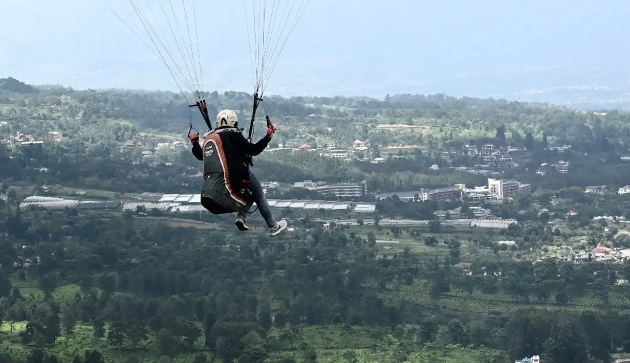 Seorang paraglider lepas landas dari lereng bukit di Puncak, Bogor, Jawa Barat, Kamis (2/12/2021). Destinasi wisata alam Bukit Paralayang Puncak Bogor sangat cocok untuk dikunjungi pada liburan akhir pekan bersama keluarga, sahabat maupun pasangan tercinta. (Goh Chai Hin/AFP)