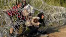 Imigran Suriah berusaha melewati pagar berduri di wilayah Hungaria dekat perbatasan Serbia, wilayah Roszke, Kamis (27/8/2015). Pemerintah Hungaria berencana untuk memperketat perbatasan bagian selatannya dari para pengungsi. (REUTERS/Bernadett Szabo)