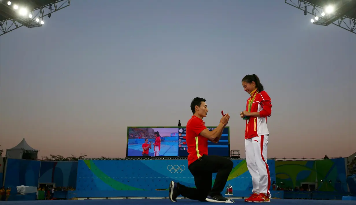 Atlet loncat indah Putri asal Tiongkok, He Zi saat dilamar kekasihnya atlet Penyelam, Qin Kia di atas panggung, saat pengalungan medali perak di ajang Lompat Indah 3 meter pada Olimpiade 2016 di Rio de Janeiro, Brasil, (14/8). (REUTERS/Michael Dalder)
