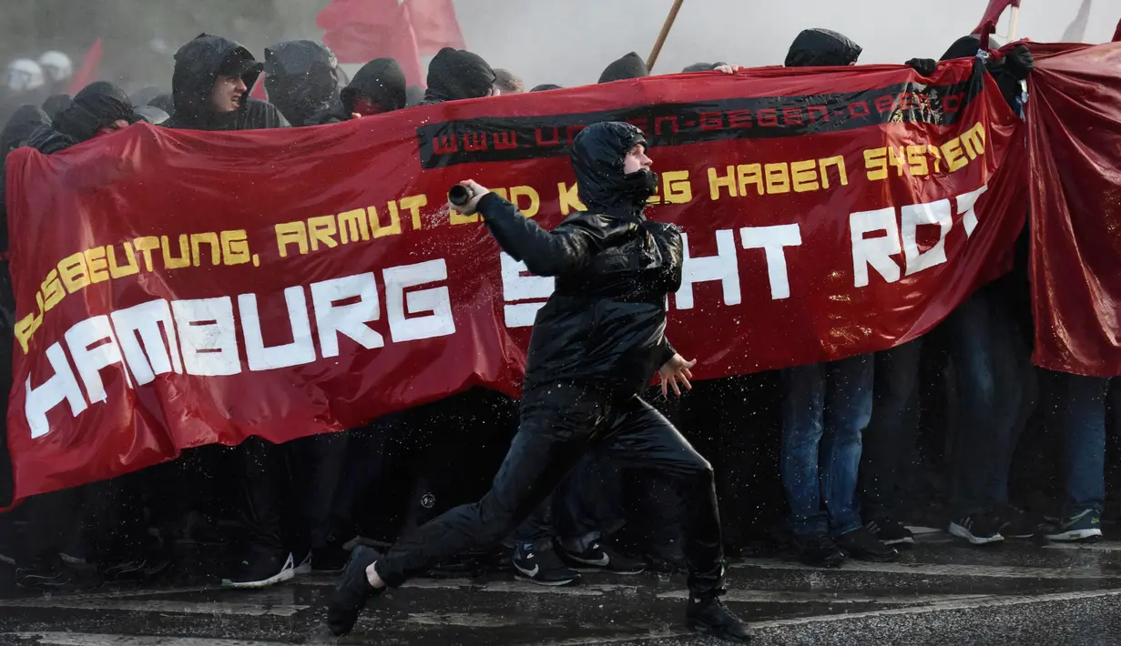 Seorang pengunjuk rasa melemparkan botol selama pawai peringatan May Day 2016 atau Hari Buruh Sedunia di Hamburg, Jerman, Minggu (1/5). Di beberapa negara, peringatan buruh sempat diwarnai dengan aksi bentrok. (REUTERS/Fabian Bimmer)