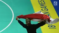 Pesilat Indonesia Sugianto membawa bendera merah putih usai meraih medali emas dalam babak final tunggal putra pencak silat seni Asian Games 2018 di Padepokan Pencak Silat Taman Mini Indonesia Indah (TMII), Jakarta, Rabu (29/8). (Merdeka.com/ Imam Buhori)