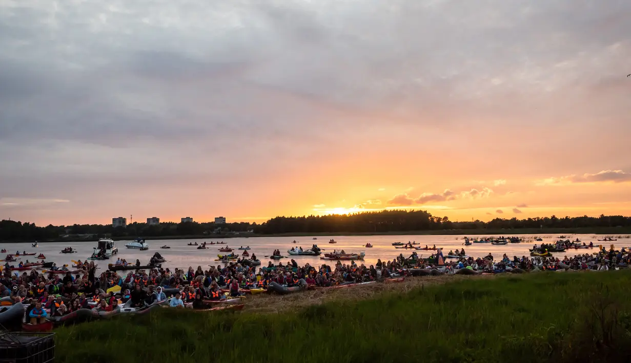 Para penonton menikmati konser musik Laivā dari atas perahu di Danau Juglas, Riga, Latvia, 14 Agustus 2021. Warga Latvia bisa menikmati konser musik dari atas kayak, sampan, dan kapal motor bahkan ketika mereka belum divaksin COVID-19. (Gints Ivuskans/AFP)