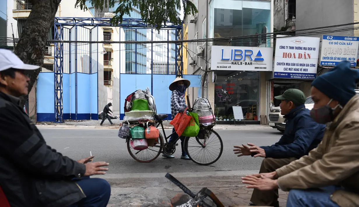 Sejumlah orang membakar kayu untuk menghangatkan diri pada hari musim dingin di Hanoi, Vietnam, Jumat (8/1/2021). Vietnam tahun ini diperkirakan mengalami musim dingin yang lebih dingin dari biasanya ketika suhu permukaan laut Samudra Pasifik turun, membentuk fenomena La Nina. (Nhac NGUYEN/AFP)