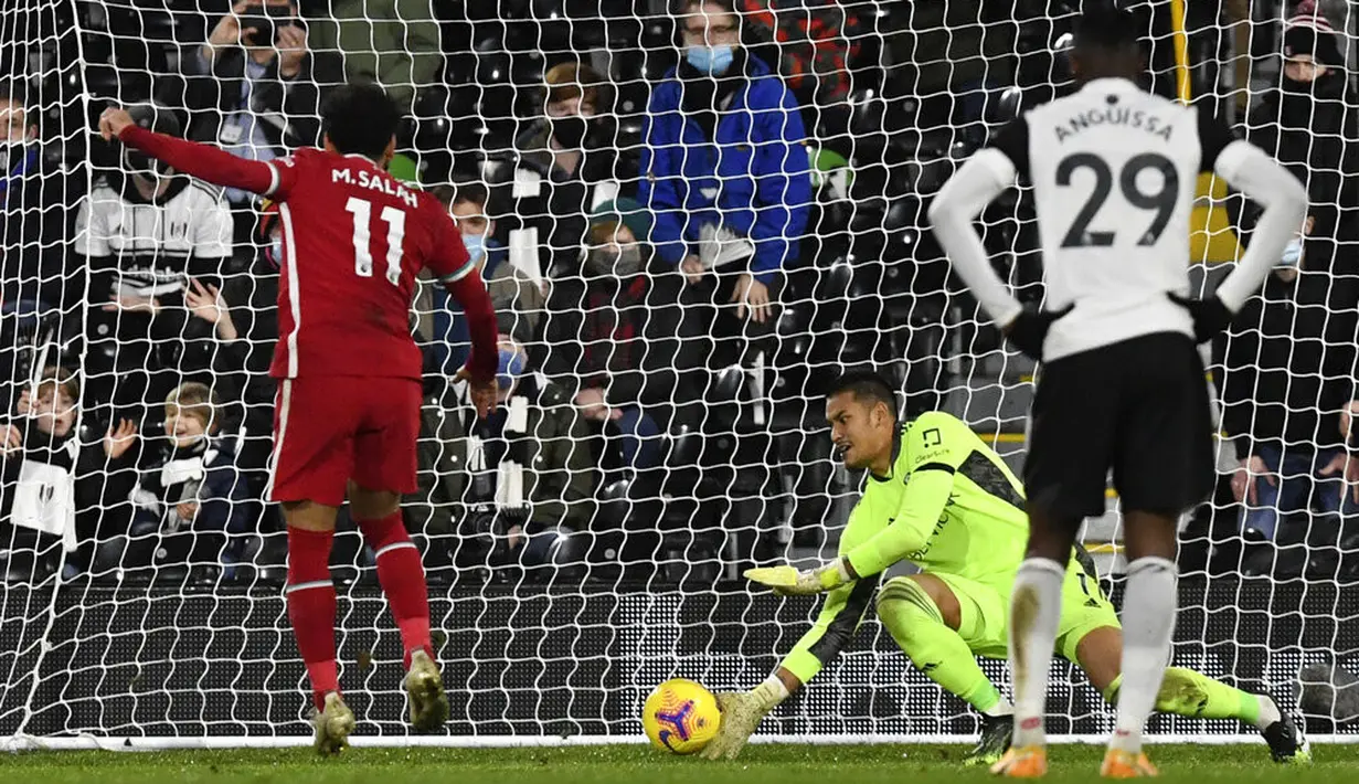 Pemain Liverpool Mohamed Salah (kiri) mencetak gol dari titik penalti ke ke gawang Fulham pada pertandingan Liga Premier Inggris di Stadion Craven Cottage, London, Minggu (13/12/2020). Liverpool dan Fulham bermain imbang 1-1. (Neil Hall/Pool via AP)