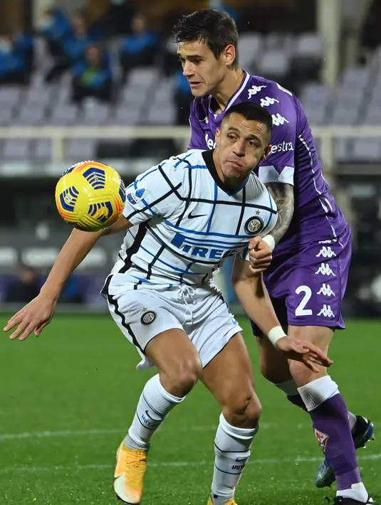 Bek Fiorentina, Lucas Martinez Quarta (kanan) menahan penyerang Inter Milan, Alexis Sanchez pada lanjutan laga Liga Italia di Stadion Artemio Franchi, Sabtu dinihari WIB (6/2/2021). Inter Milan mengalahkan Fiorentina 2-0 dan menggusur AC Milan dari puncak klasemen Serie A.  (Alberto PIZZOLI/AFP)
