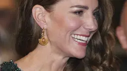 Kate Middleton, Duchess of Cambridge tersenyum selama Royal Variety Performance di Royal Albert Hall, London (18/11/2021). Kate menata rambutnya dengan ikal glamor yang jatuh ke satu sisi, meningkatkan penampilannya dengan anting-anting emas dan clutch hitam. (AFP/Justin Tallis)
