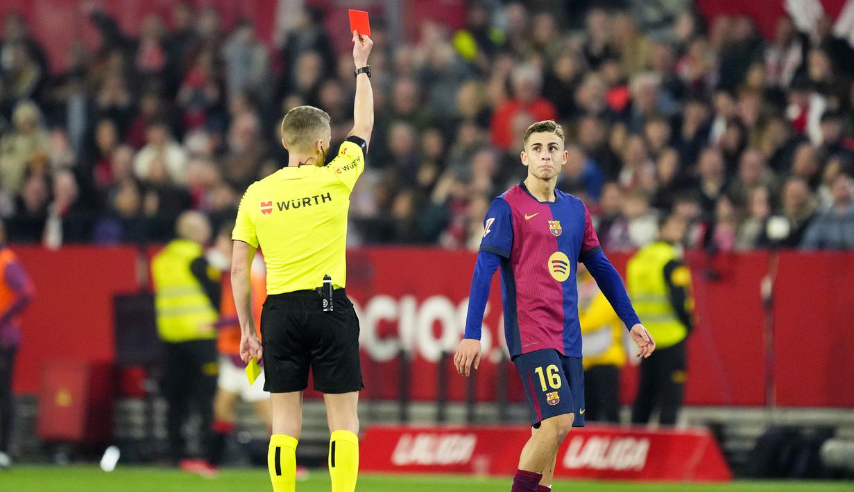 Pemain Barcelona, Fermin Lopez diganjar kartu merah oleh wasit setelah melakukan tekel keras kepada pemain Sevilla, Djibril Sow dalam laga lanjutan Liga Spanyol 2024/2025 di Ramon Sanchez Pizjuan Stadium, Sevilla, Spanyol, Senin (10/02/2025) dini hari WIB. (AP Photo/Jose Breton)