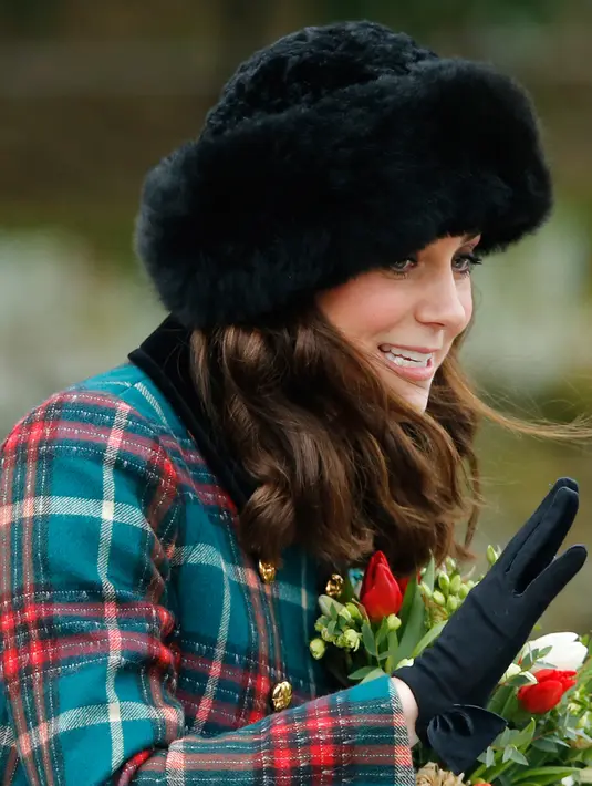Kate Middleton menyapa warga setelah tradisi kebaktian Hari Natal Kerajaan Inggris di Gereja St. Mary Magdalene, Sandringham, Senin (25/12). Penampilan cantik Kate Middleton dilengkapi dengan pillowbox hat beraksen bulu bwarna hitam. (AP/Alastair Grant)