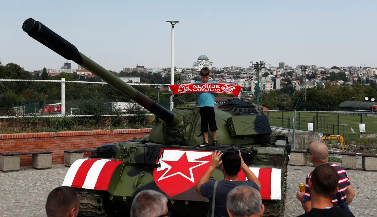 Suporter Red Star Belgrade berpose di tank T-55 yang terparkir di tribun utara Stadion Rajko Mitic, Belgrade, Serbia, Selasa (27/8/2019). Laman resmi klub suporter Red Star Belgrade menyatakan tank itu mewakili slogan mereka: "Mesih sudah dihidupkan." (AP Photo/Darko Vojinovic)