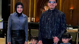 Aurel tampil chic dengan atasan abu-abu bertekstur yang dipadukan dengan celana hitam berpotongan sleek, sementara hijab hitamnya memberi sentuhan klasik yang rapi. [@aurelie.hermansyah],