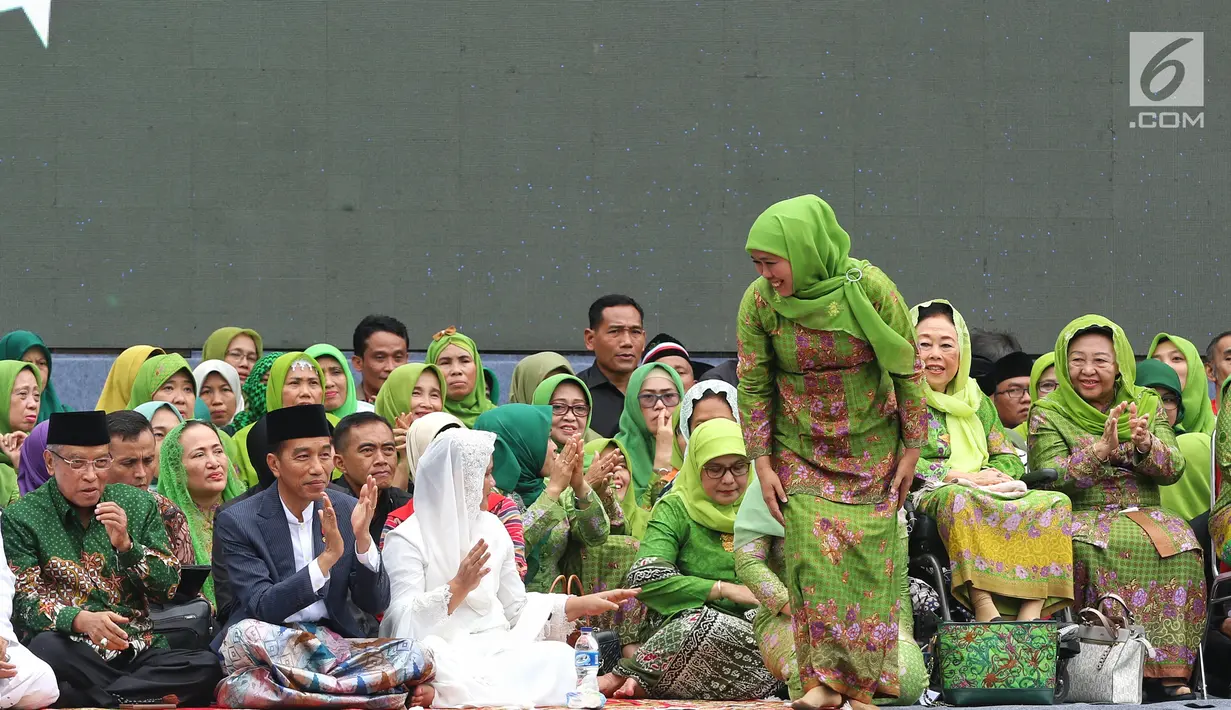 Ketua Umum PP Muslimat NU Khofifah Indar Parawansa tersenyum ke arah Presiden Joko Widodo atau Jokowi saat akan memberi sambutan dalam Harlah ke-73 Muslimat NU di SUGBK, Jakarta, Minggu (27/1). (Liputan6.com/Johan Tallo)