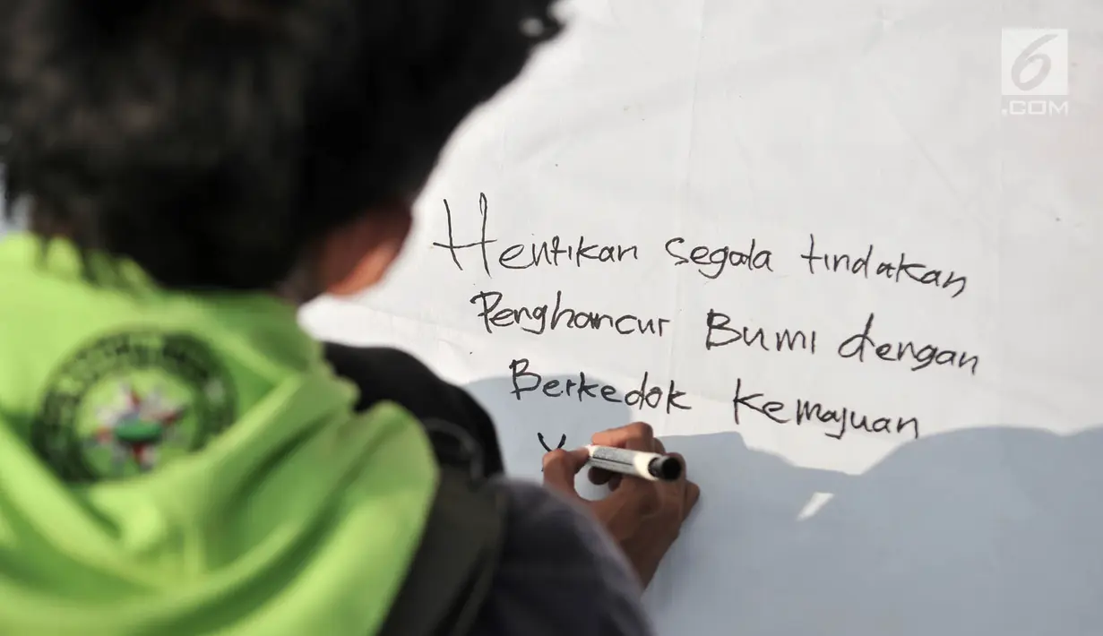 Seorang pria menuliskan pesan pada kain saat peringatan Hari Bumi di CFD Bundaran HI, Jakarta, Minggu (21/4). Aksi ini untuk memperingati Hari Bumi yang jatuh pada 22 April. (merdeka.com/Iqbal Nugroho)