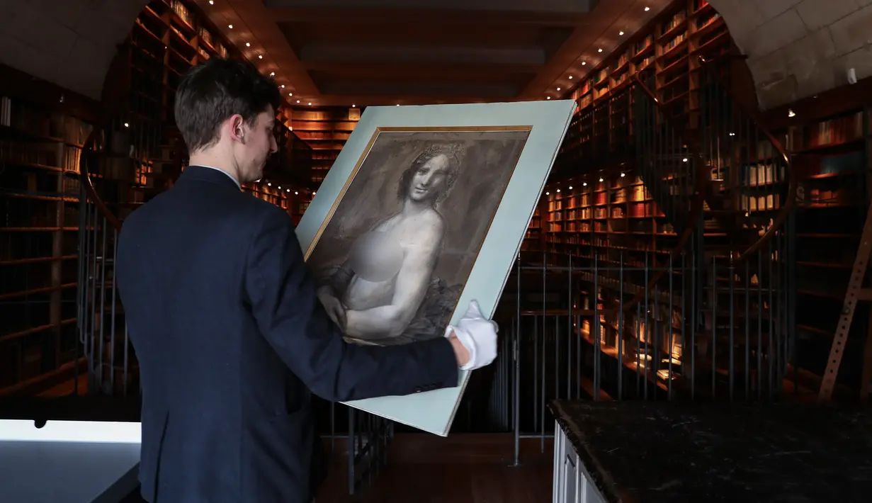 Kurator Mathieu Deldicque memegang lukisan 'Monna Vanna' atau dikenal dengan 'Mona Lisa Telanjang' di Museum Conde, Chantilly, Prancis, Senin (11/3). Lukisan tersebut akan dipajang dalam pameran khusus pada akhir tahun 2019. (Kenzo Tribouillard/AFP)