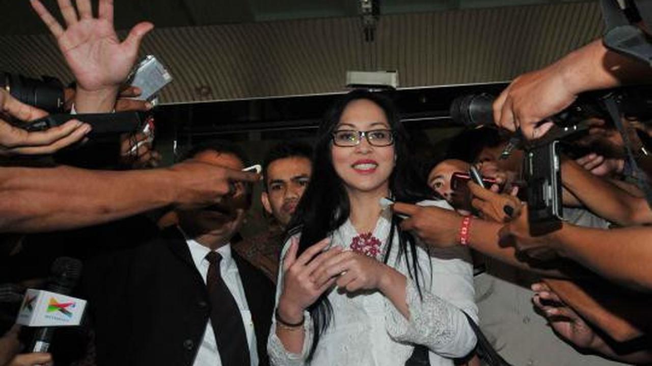 Angelina Sondakh tersenyum saat dikawal petugas keamanan KPK dan polis 