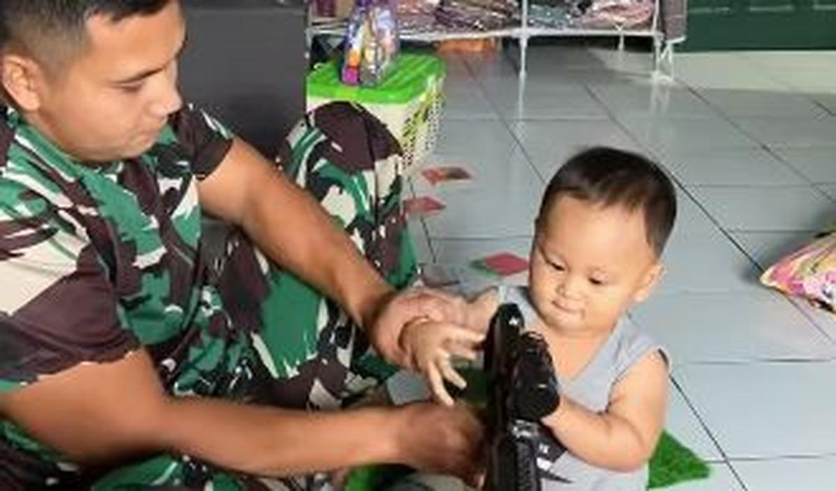 Lebih lanjut, sang ayah memberikan senjatanya kepada jagoan kecilnya. Dengan sabar, ia seolah memberikan arahan bagaimana cara menembak yang benar dan tepat. <br>