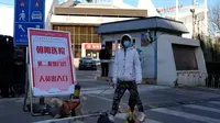 Seorang warga berjalan-jalan dengan anjingnya melewati klinik demam kedua yang baru dibuka di Rumah Sakit Chaoyang, Beijing, China, Kamis (15/12/2022). Seminggu setelah China melonggarkan beberapa tindakan pengendalian COVID-19 yang paling ketat di dunia, ketidakpastian masih ada mengenai arah pandemi di negara dengan jumlah penduduk terpadat di dunia tersebut. (AP Photo/Ng Han Guan)