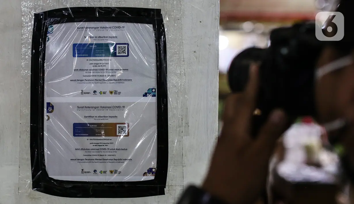 Pewarta memotret tembok yang dipasang sertifikat vaksin Covid-19 di Pasar Santa, Jakarta, Minggu (5/9/2021). Berbagai upaya dilakukan pedagang Pasar Santa untuk menarik pelanggan di masa PPKM level 3, salah satunya dengan memasang stiker sertifikat vaksin di beberapa ruko. (Liputan6.com/Johan Tallo)