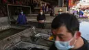 Para pedagang mengenakan masker saat berjualan di Pasar Baishazhou Wuhan di Wuhan, provinsi Hubei, Rabu (15/4/2020). Lebih dari 90 persen kios pasar basah di Wuhan telah kembali buka sejak pemerintah mencabut aturan lockdown di wilayah pusat pandemi corona tersebut. (Hector RETAMAL/AFP)
