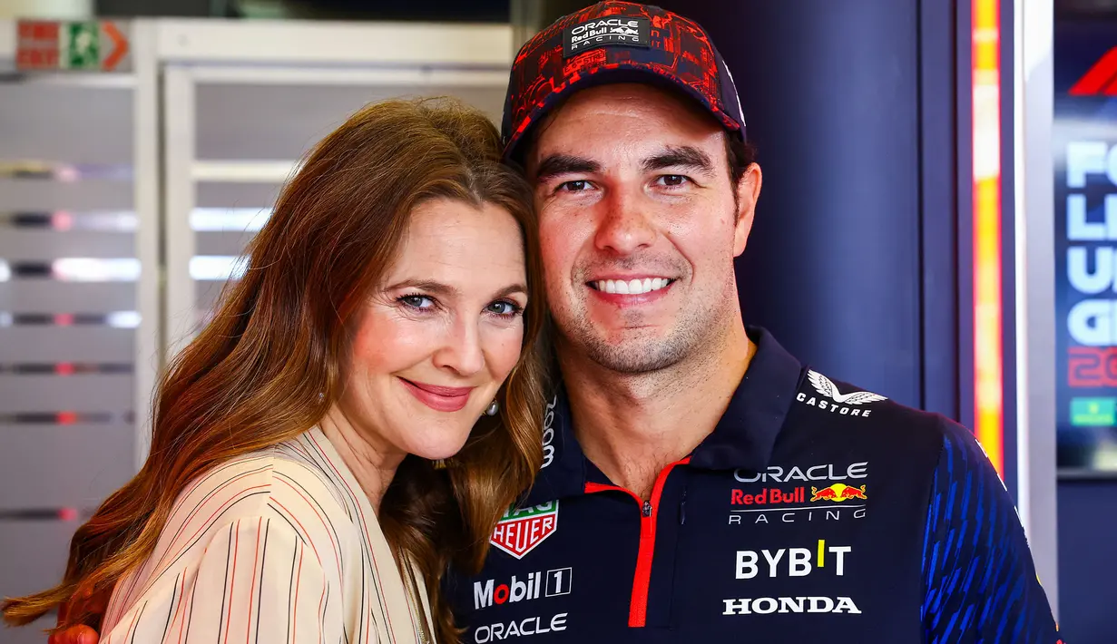 Aktris Amerika Serikat, Drew Barrymore (kiri) berfoto bersama salah satu pembalap Red Bull, Sergio Perez saat mengunjungi paddock tim Red Bull Racing menjelang Formula 1 GP Amerika Serikat 2023 di Circuit of The Americas, Austin, Texas, Kamis (19/10/2023) waktu setempat. (AFP/Mark Thompson)