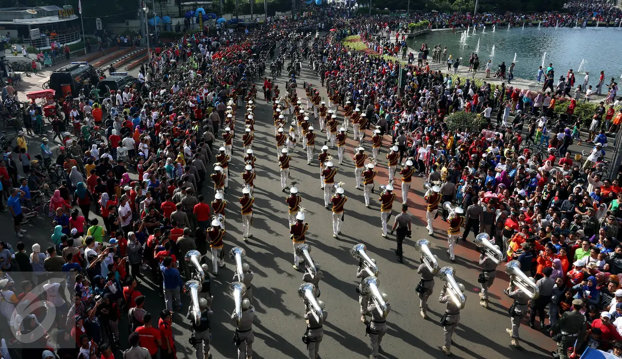 Warga memadati pinggiran jalan di kawasan Bundaran HI saat parade bendera digelar, Jakarta, Minggu (30/10). Parade ini merupakan rangkaian arak-arakan parade Bendera Menjelang Sidang Umum Interpol Ke-85. (Liputan6.com/Johan Tallo)
