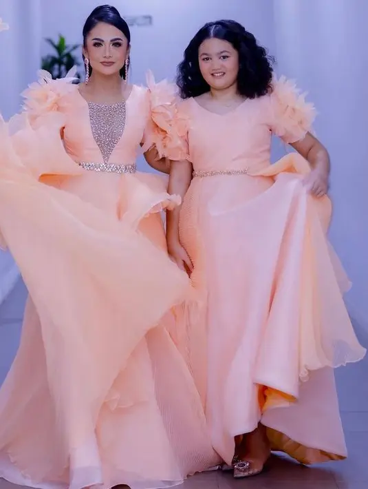 Mereka mengenakan gaun berwarna peach yang dengan detail feather di lengan. (Instagram/@krisdayantilemos).