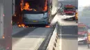 Petugas tengah berusaha memadamkan api yang membakar badan bus Transjakarta di kawasan Salemba, Jakarta, Jumat (3/7/2015). Kobaran api tampak membakar bus gandeng berwarna abu-abu itu, bahkan api juga menyambar bagian halte. (twitter.com/PT_TransJakarta)