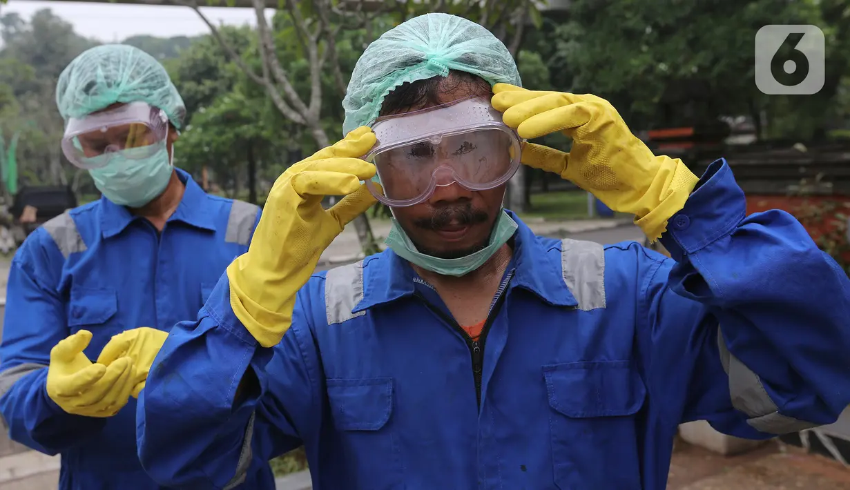 Petugas memasang kacamata dan masker sebelum menyemprotkan cairan disinfektan di area Museum Fauna Indonesia Komodo dan Taman Reptilia, TMII Jakarta, Rabu (18/3/2020). Pengelola TMII secara bertahap melakukan tindakan disinfeksi di setiap lokasi wisata dan anjungan. (Liputan6.com/Fery Pradolo)