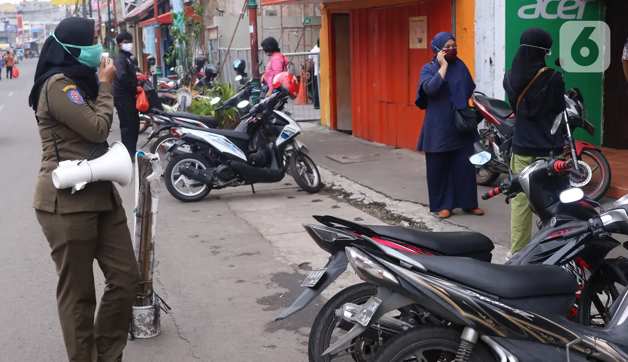 Petugas Satpol PP mengimbau warga untuk menggunakan masker dan menjaga jarak di Pasar Lama, Kota Tangerang, Banten, Sabtu (9/6/2020). Pemkot Tangerang melakukan penegasan pada PSBB tahap dua dengan menugaskan petugas di keramaian guna memutus rantai penyebaran COVID-19.  (Liputan6.com/Angga Yuniar)