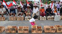Seorang anak berjalan di antara kotak aksi protes memasung kaki dengan semen di depan Istana Merdeka, Kamis (16/3). Para petani juga meminta untuk menghentikan kegiatan penambangan karst oleh pabrik semen.(Liputan6.com/Fery Pradolo)