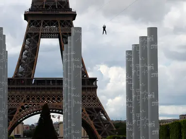 Pengunjung meluncur dengan seutas tali saat melakukan permainan Zip Line dari lantai dua Menara Eiffel di atas taman Champ de Mars, Paris, Selasa (28/5/2019). Kegiatan yang mirip dengan flying fox ini dipasangkan di atas ketinggian 115 meter dengan kecepatan 30 km per jam. (AP/Francois Mori)