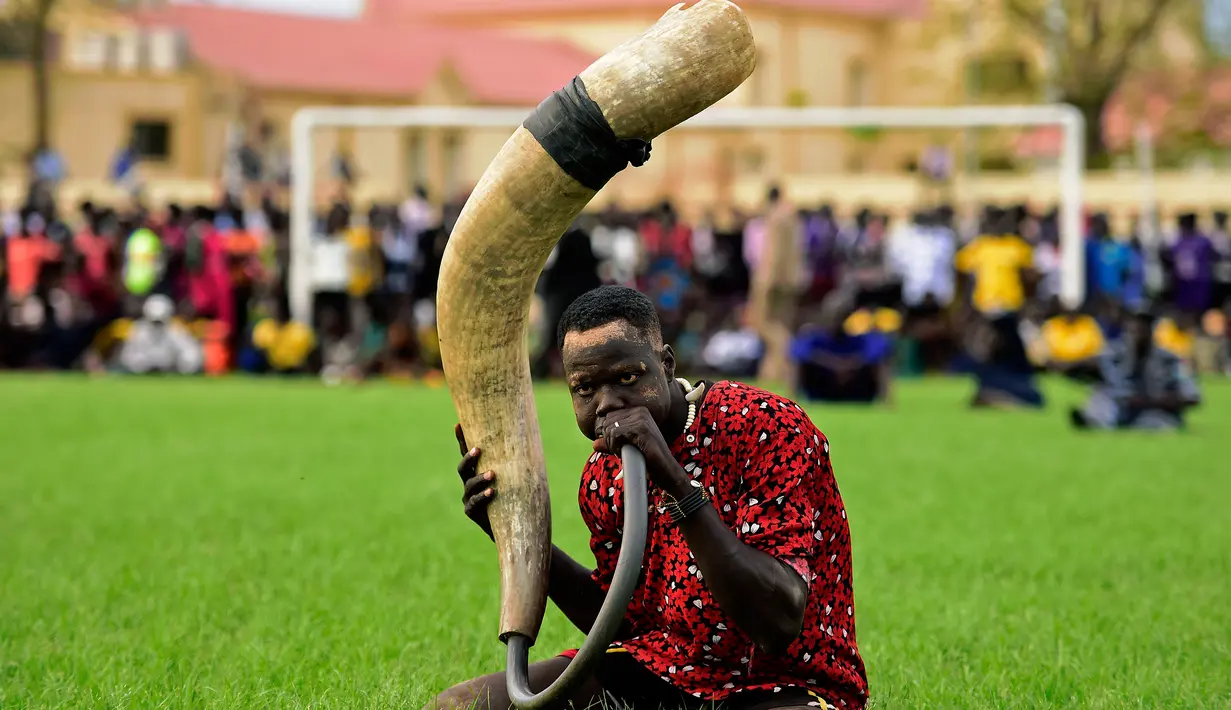 Seorang penonton membunyikan terompet tradisional saat Kompetisi Gulat Nasional Sudan Selatan di Stadion Juba, Sudan (20/4).Turnamen besar ini pernah dihentikan saat perang saudara terjadi pada bulan Desember tahun 2013. (CARL DE SOUZA / AFP)