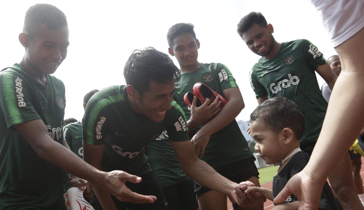 Pemain Timnas Indonesia U-23, Hanif Sjahbandi, menyapa seorang anak yang datang ke Stadion Madya, Jakarta, Rabu (13/3). Sejumlah anak dari Yayasan Rumah Harapan Indonesia datang menemui Timnas U-23 (Bola.com/Vitalis Yogi Trisna)