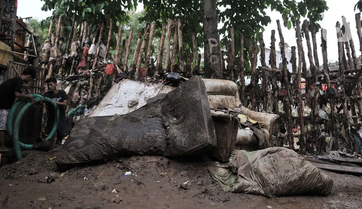 Kondisi tanggul kayu yang rusak dan penuh sampah di bantaran Kali Ciliwung, Rawajati, Pancoran, Jakarta, Minggu (5/1/2020). Tanggul dari kayu dolken dan karung pasir yang baru dibangun pada akhir Desember 2019 itu rusak hingga dipenuhi sampah akibat terjangan arus banjir. (merdeka.com/Iqbal Nugroho)