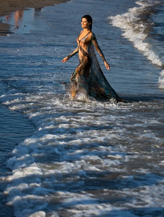 Model asal Brasil Isabeli Fontana berjalan di pantai saat sesi pemotretan selama Festival film Venice ke-74 di Venice, Italia (30/8). Model 34 tahun ini tampil dengan gaun transparan saat sesi pemotretan di pantai. (AP Photo / Domenico Stinellis)