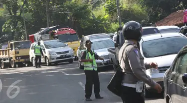 Petugas berusaha mengatur kemacetan kendaraan yang melintas di jalur lingkar Nagreg, Jawa Barat, Sabtu (2/7). Kemacetan disebabkan bus pemudik yang mengalami kecelakaan hingga menutup sebagian jalur. (Liputan6.com/Immanuel Antonius)