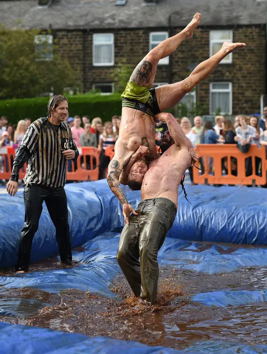 Pegulat membanting lawannya saat mengikuti World Gravy Wrestling Championships ke-10 di Rose 'n' Bowl Pub di Inggris (28/8). Pertandingan gulat ini cukup unik, karena digelar di sebuah kolam selam dua menit. (AFP Photo/Oli Scarff)