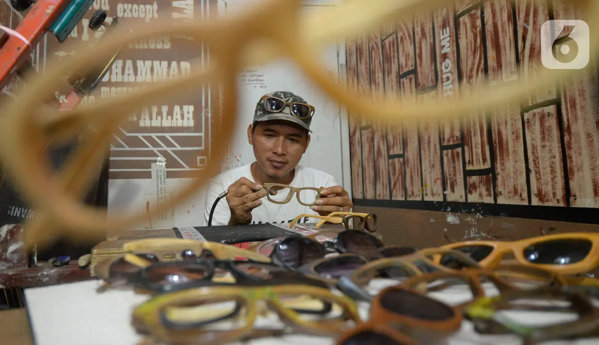 Perajin Yuyud Wahyudi (39) menyelesaikan pembuatan frame kacamata dari limbah kayu bekas di Pondok Benda, Pamulang, Tangsel, Kamis (8/10/2019). Sebelum pandemi, Yuyud menerima banyak pesanan seperti dari Italia, Norwegia, Prancis dan Jerman, namun kini turun hingga 75 persen. (merdeka.com/Dwi Narwok