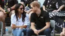 Pangeran Harry dan kekasihnya Meghan Markle menonton pertandingan tenis kursi roda selama Invictus Games 2017 di Toronto, Kanada, Senin (25/9). Selama pertandingan, keduanya tampak akrab, sambil sesekali berbisik satu sama lain. (AP Photo)