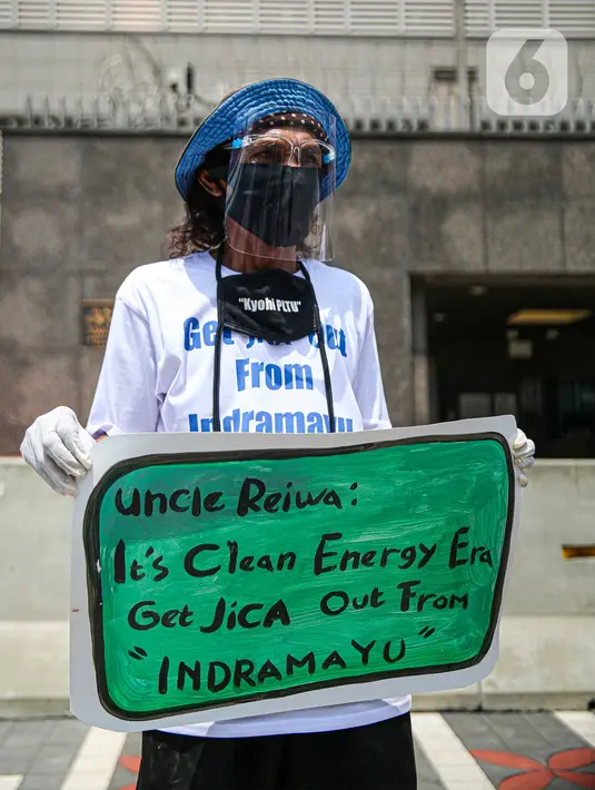 Seorang warga dari Indramayu membawa poster saat menggelar aksi di depan Kedubes Jepang, Jakarta, Rabu (21/10/2020). Dalam aksinya, mereka menolak pembangunan PLTU 2 di Indramayu karena akan menyebabkan pencemaran udara dan rusaknya lahan pertanian. (Liputan6.com/Faizal Fanani)