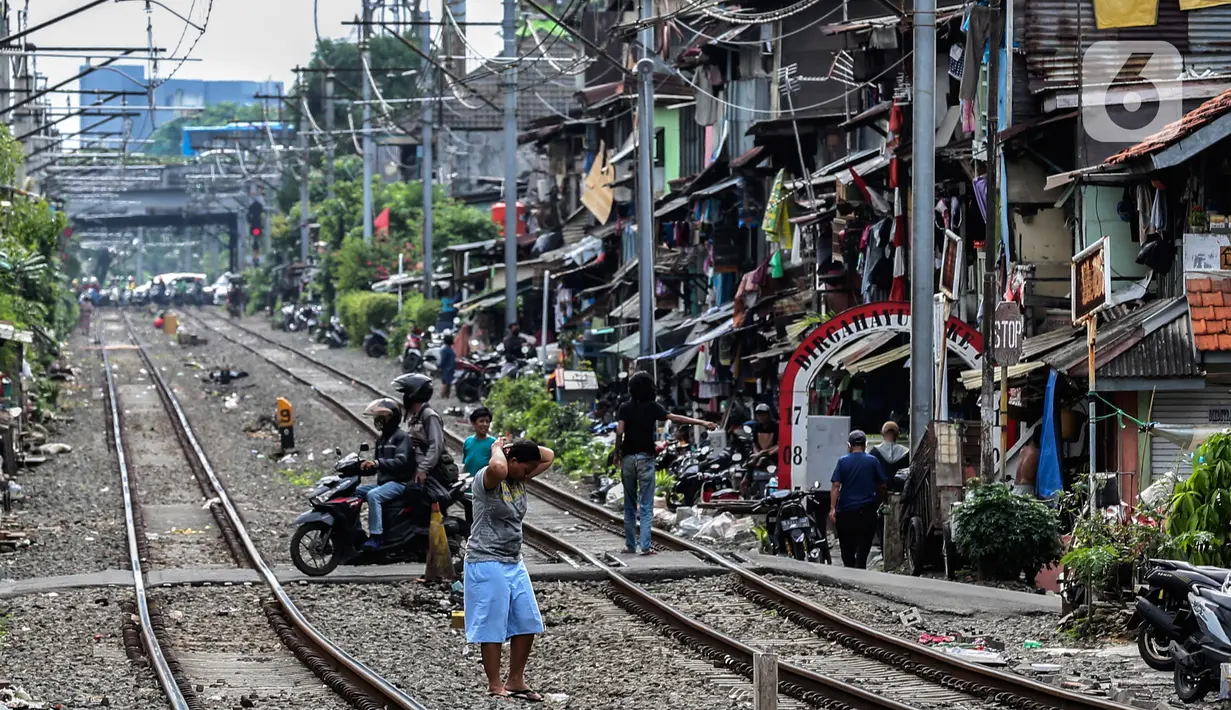 Pengendara motor melintas di bantaran rel kawasan pemukiman padat Pejompongan di tengah pandemi COVID-19, Jakarta, Kamis (28/1/2020). Sensus Penduduk 2020 (SP2020) mencatat penduduk DKI Jakarta pada bulan September 2020 sebanyak 10,56 juta  jiwa. (Liputan6.com/Johan Tallo)